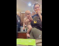 Mother holding baby spits out mango peels and baby enjoys