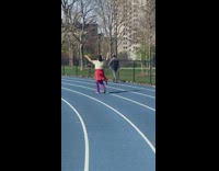 Lady walks around track with arms raised 