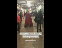 Man walks through subway station wearing a long red cape