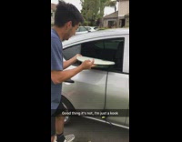 man in blue stuffs surf board in silver car