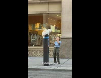 Man puts white dog onto parking meter and takes a picture of it on his phone