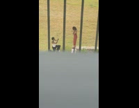 Woman in brown dress bends while man takes picture