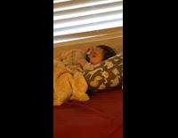 Baby eyes closed in bed stressed touching head