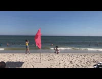 Yellow shirt girl walks beach red flag 