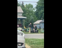 Guy sitting on a kids car holds up selfie stick 