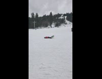 Woman slides down slope on snowboard, trips backwards and plays it off by striking a pose on the floor