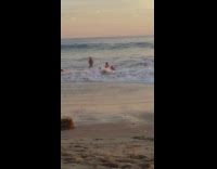 Several guys in the water keep getting knocked down by the waves 