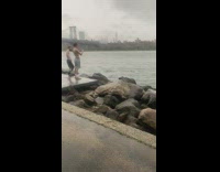 Man wears jumper outfit while on the beach rocks