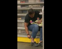 Woman sits on subway stairs and files down the heels of her feet with filer