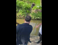 Guy vaults himself across stream with stick