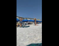 Girl brown hat kneel beach blue umbrella
