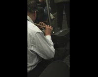 man plays brown flute in subway 