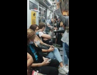 Man plays music on small piano on crowded train