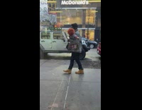 Guy on sidewalk carrying chucky doll as baby