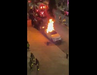 White car on fire parked on the street