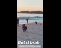 Brown shorts denim jacket guy jumps beach 