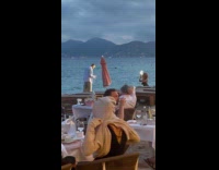 Man with glass poses at beach restaurant