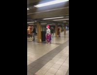 Clowns in colorful wigs gather around in subway station
