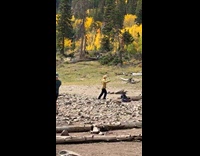 Woman yellow checkered top dances mountain behind