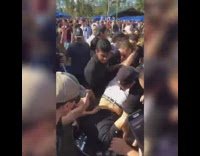 A guy in a black shirt is getting dumped in a bucket of ice, then chugs beer 