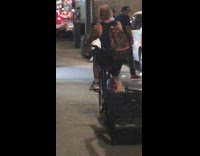 Man drags black luggage back of bike