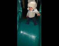 Dad helps baby on small slide slide down