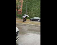 Woman in blue jacket sits while it rains