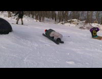 Guy skis on black rail tube, trips over and falls in snow
