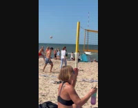 Couple play volleyball pass with dog on beach