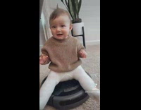 Baby girl sits and rides roomba vacuum 