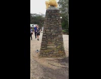 Woman yellow pants on top of rock statue