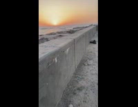 Guy walks by ocean water orange sunset 
