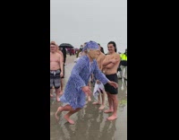 Guy in pajamas and costume mask runs into ocean 