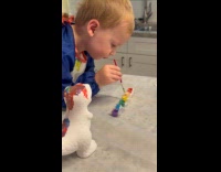 Kid dips paintbrush on all paints before painting