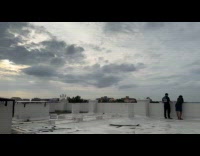 Two guys on rooftop clouds time lapse