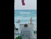 Woman takes picture with table in the water at beach