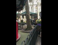 Woman models on a spinning carousel, photographer takes picture and uses leafblower