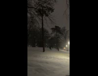 Guys ride snowboard at park snow night