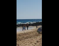Three women in hold hands and walk at the beach