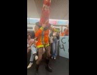 Women in traffic cone costume inside train