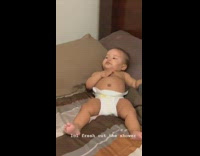 Baby in diaper laying in bed relaxing watching tv