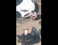 Grey shirt guy squats poses white car 