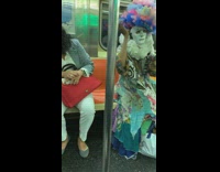 Woman in blue scrap fabric dress and rainbow tulle tissue headpiece  on subway train