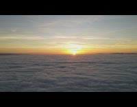 Aerial drone view of sunset above clouds