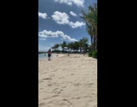 Woman pink bikini kneels at the beach