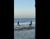 Man pulls woman white shirt ground beach