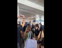 Group singing waits for flight at airport