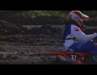 Guy rides orange dirt bike around course 
