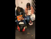 Man and woman eat out of Reeses chocolate candy box on subway train
