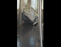 Person covered in thermal blanket on subway train